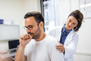 A female doctor at the clinic performs auscultation of the lungs of a patient with symptoms of coronavirus or pneumonia. photo