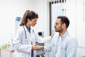 Young female doctor hold hand of caucasian man patient give comfort, express health care sympathy, medical help trust support encourage reassure infertile patient at medical visit photo