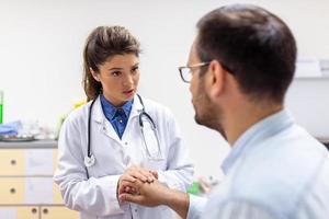 Young female doctor hold hand of caucasian man patient give comfort, express health care sympathy, medical help trust support encourage reassure infertile patient at medical visit photo