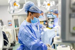 Concentrated Surgical team operating a patient in an operation theater. Well-trained anesthesiologist with years of training with complex machines follows the patient throughout the surgery. photo