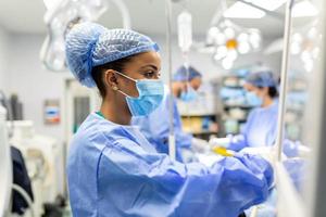 Concentrated Surgical team operating a patient in an operation theater. Well-trained anesthesiologist with years of training with complex machines follows the patient throughout the surgery. photo