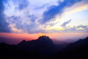 puesta de sol en cielo y nube, hermosa vistoso crepúsculo hora con silueta de montaña. foto