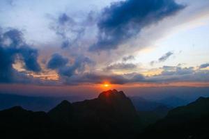 puesta de sol en cielo y nube, hermosa vistoso crepúsculo hora con silueta de montaña. foto