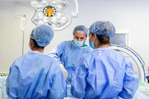 Medical team of surgeons in hospital doing minimal invasive surgical interventions. Surgery operating room with electrocautery equipment for cardiovascular emergency surgery center. photo