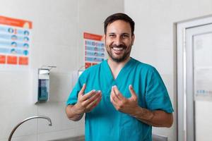 Doctor washing hands with soap. Male surgeon is preparing for surgery. He is in uniform photo