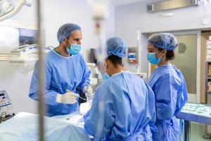 el equipo de un cirujano uniformado realiza una operación a un paciente en una clínica de cirugía cardíaca. medicina moderna, un equipo profesional de cirujanos, salud. foto