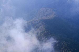 Golden light with sunrise in morning on the sky and clound on the mountain. Fog cover the jungle hill in Thailand photo