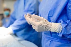 retrato de una hermosa doctora cirujana poniéndose guantes médicos en la sala de operaciones. cirujano en quirófano moderno foto