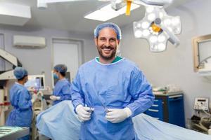 retrato de cirujano masculino en quirófano mirando a la cámara. médico en matorrales y mascarilla médica en el quirófano de un hospital moderno. foto