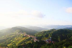 Aerial view Hill tribe village and Tea Plantation in sunrise on the mountain and forest is very beautiful flowers meadow in Chiangrai Province, Thailand photo