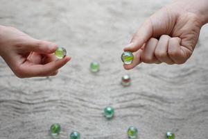 Closeup hands holds round small mable balls to play games. Concept, traditional childen play toy. Recreation activity to make concentrate for kids, fun and competition games photo