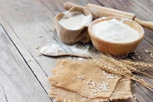 Soft focus, flour in a wooden bowl, ears of wheat, barley, cooking, bread, and cookies arranged on a wooden tabletop in a rustic kitchen, top view. photo