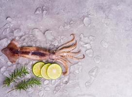 crudo calamar en hielo con limón ajo especia ensalada en negro de madera mesa fondo, Fresco calamar para cocido comida a un cocina restaurante o Mariscos mercado foto