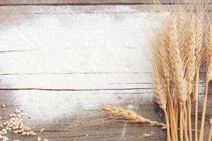 Flour and ears of wheat, barley, cooking, bread, and cookies were arranged on the wooden table background in a rustic kitchen. Top view. photo