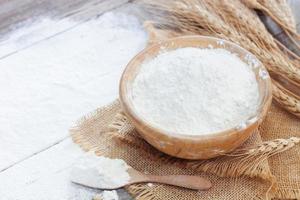 Soft focus, flour in a wooden bowl, ears of wheat, barley, cooking, bread, and cookies arranged on a wooden tabletop in a rustic kitchen, top view. photo