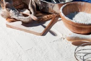 Flour and ears of wheat, barley, cooking, bread, and cookies were arranged on the wooden table background in a rustic kitchen. Top view. photo