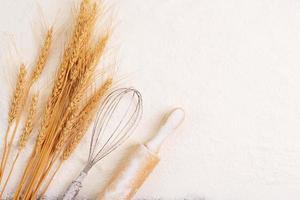 Flour and ears of wheat, barley, cooking, bread, and cookies are arranged on the table in a rustic kitchen, top view. photo