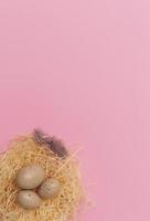 Easter eggs and feather in a nest on pastel pink Background. Minimal creative layout with copy space. Top view. Flat lay. photo