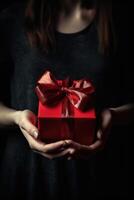 Gift box with red ribbon bow in female hands. photo