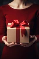 Gift box with red ribbon bow in female hands. photo