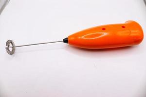 Orange coffee mixer on white background,handheld milk frother photo