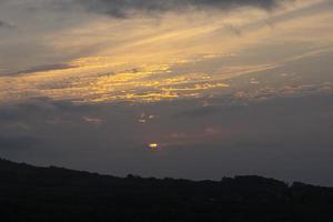 Dawn in the mountains, the sun rises among the clouds forming many rays of light photo