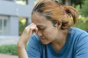 Asian women sitting at park feel a headache or dizzy, feeling tired. need painkillers photo