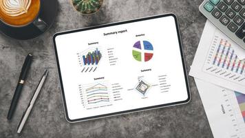 Tablet with charts and reports on office desk workplace. Top view flat lay. photo