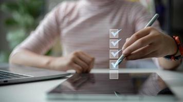 In the business performance checklist concept, businesswomen use tablets to do online checklist surveys and fill out digital form checklists. photo