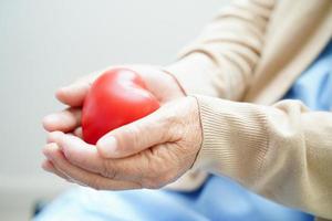 Asian elder senior woman patient holding red heart in hospital. photo