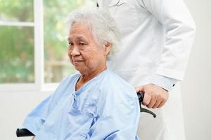 Doctor help Asian elderly woman disability patient sitting on wheelchair in hospital, medical concept. photo