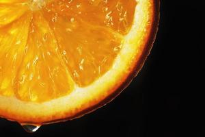 naranja rebanada con un soltar de agua cerca arriba en un negro antecedentes foto