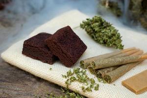 pre anuncio canabis articulaciones y pastel Brownies con marijuana brotes tendido en el arpillera foto