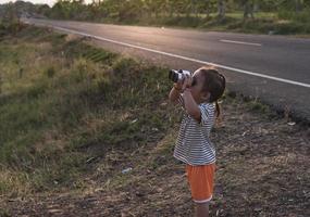 linda niña mirando mediante prismáticos, concepto de senderismo, cámping y aventura. foto