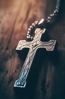 Close-up of a silver cross on a wooden table, shallow depth of field photo