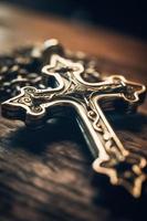 Close-up of a silver cross on a wooden table, shallow depth of field photo