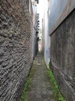 very narrow alley with walls of houses on both sides and with paving blocks path photo