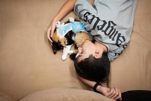 adolescente con gato dormido en un vendaje después de la cirugía. cuidado de una mascota después de la esterilización de la operación cavitaria. foto