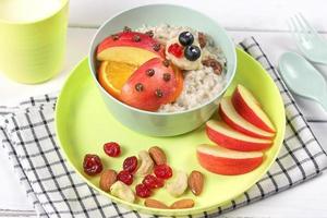 Creative food for kids. Oatmeal with fruits in the form of a ladybug in a beautiful colorful dish. Healthy and fun food. photo