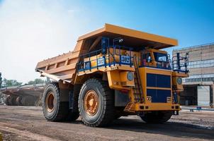 Quarry yellow dump truck drives alone industrial area at sunny day photo