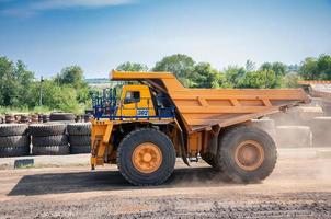 Quarry yellow dump truck drives alone industrial area at sunny day photo