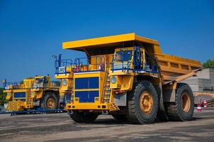 Quarry yellow dump truck drives alone industrial area at sunny day photo