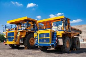 heavy yellow open cast mine dump trucks at repair station at sunny cloudless day photo