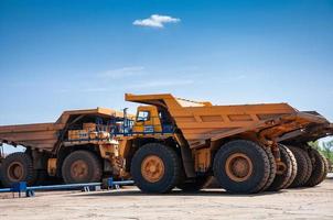 heavy yellow open cast mine dump trucks at repair station at sunny cloudless day photo