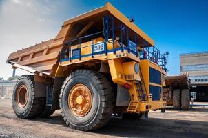 heavy yellow open cast mine dump trucks at repair station at sunny cloudless day photo