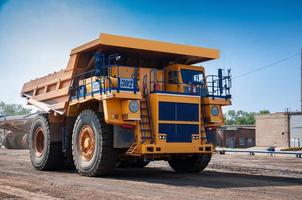 heavy yellow open cast mine dump trucks at repair station at sunny cloudless day photo