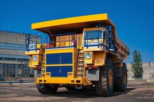 heavy yellow open cast mine dump trucks at repair station at sunny cloudless day photo