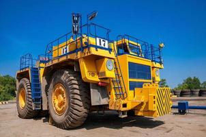 Heavy yellow quarry tractor at repair station at sunny cloudless day photo