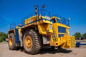 Heavy yellow quarry tractor at repair station at sunny cloudless day photo