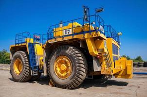 Heavy yellow quarry tractor at repair station at sunny cloudless day photo